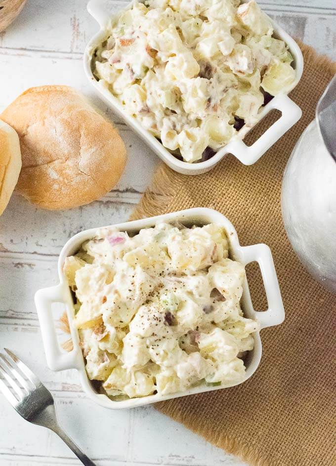 Red Potato Salad served in white bowls at picnic.