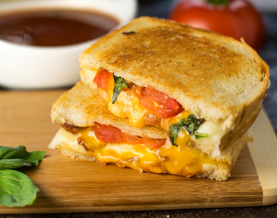 Gourmet grilled cheese with bacon, roasted tomato, and basil.