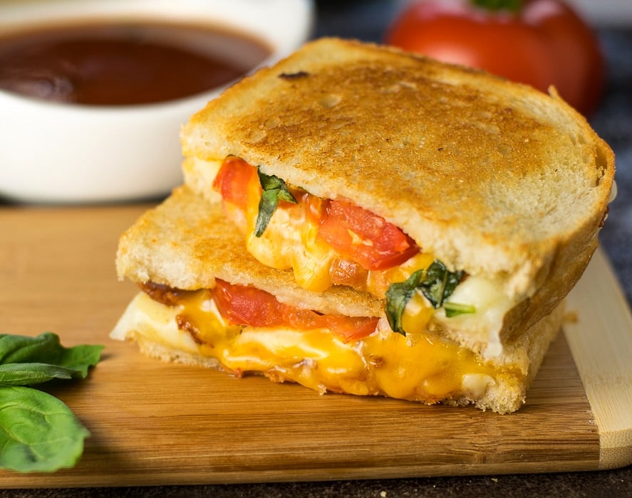 Gourmet grilled cheese with bacon, roasted tomato, and basil.