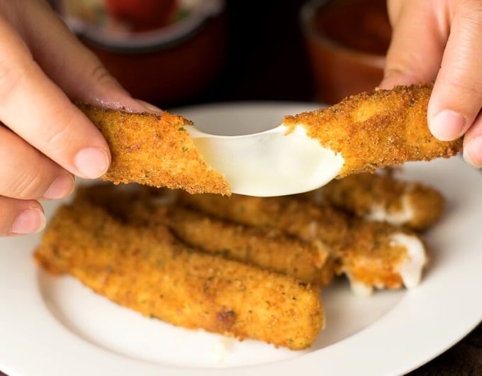 Deep fried mozzarella sticks being stretched.