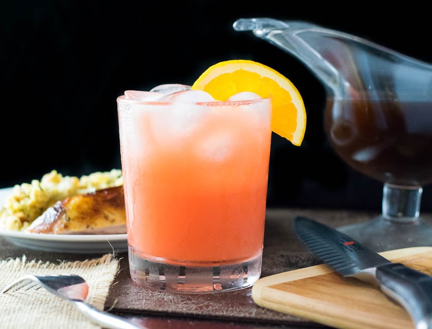 Cranberry orange juice cocktail with orange slice.