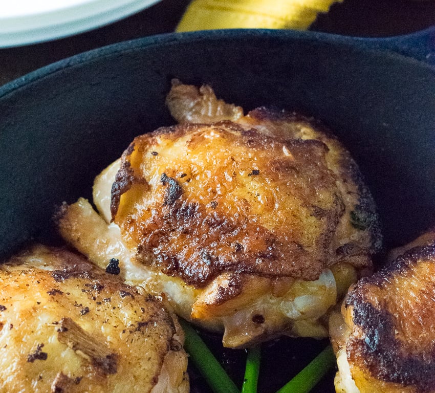 Brined chicken thigh in skillet.