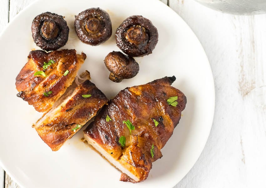 Serving smoked bacon wrapped chicken breast with a side of mushrooms.