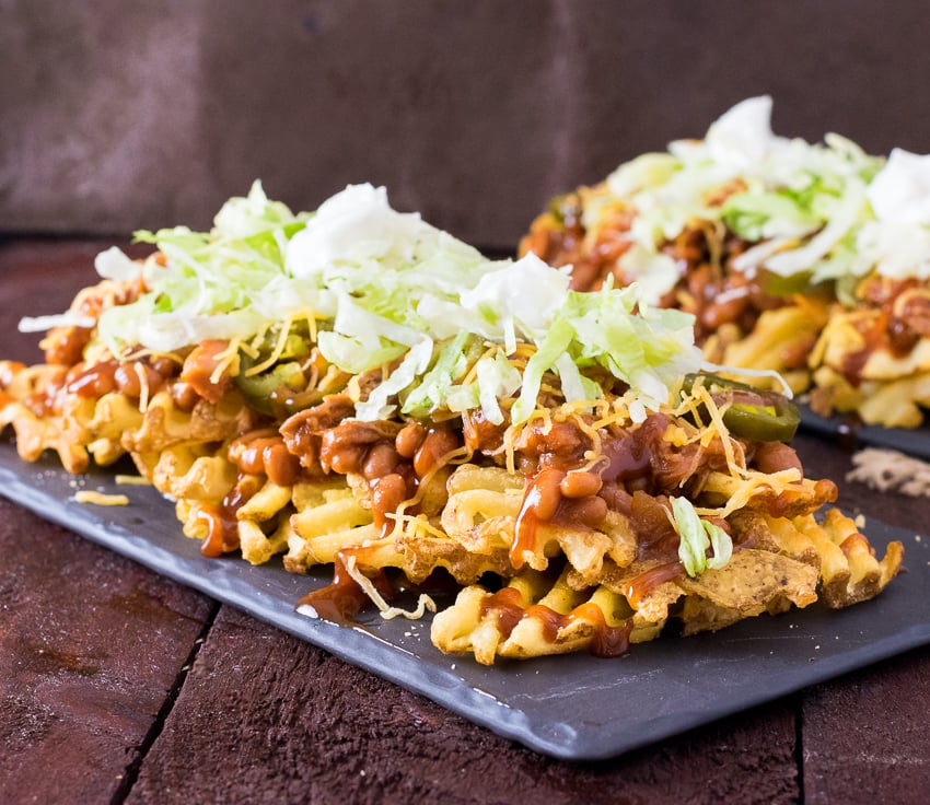 BBQ Irish Nachos piled high and shown close up with sauce dripping down.