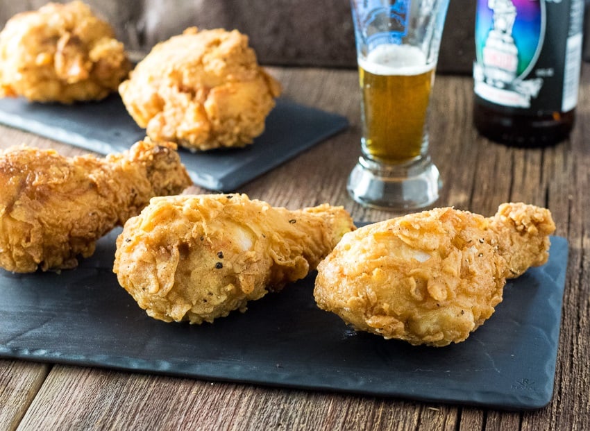 Crispy Beer Fried Chicken shown close up sitting on wooden surface.