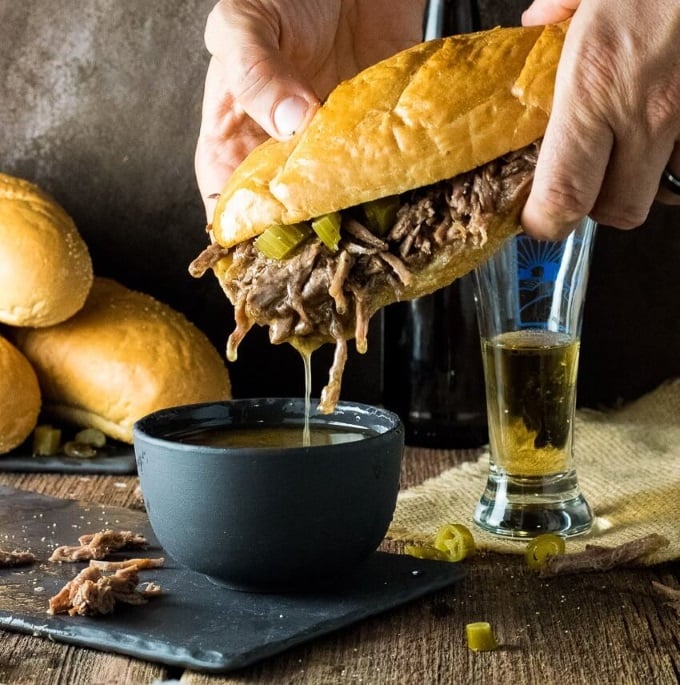 Slow Cooker Italian Beef Sandwiched being dunked in juices.