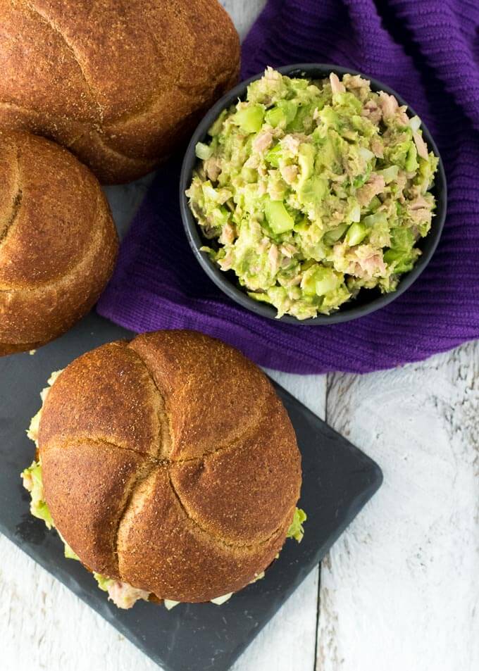 Avocado Tuna Salad served in a bowl with whole wheat buns sitting nearby.