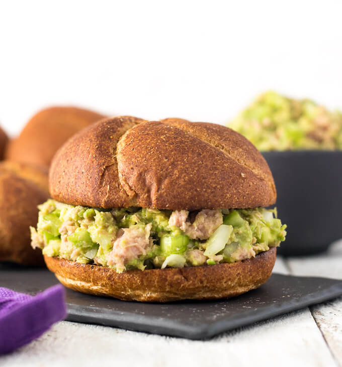 Avocado Tuna Salad sandwich on a whole wheat bun and black plate.