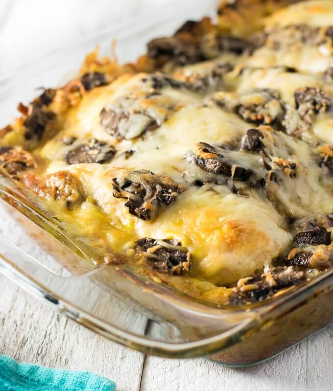 Hot pan with baked chicken covered by portobello mushrooms and melted swiss cheese