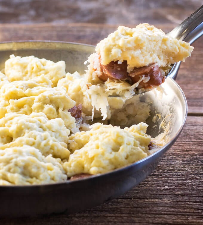 Sauerkraut and Dumplings with Kielbasa being scooped from skillet