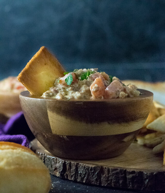 Sausage Dip with chip in wood bowl.
