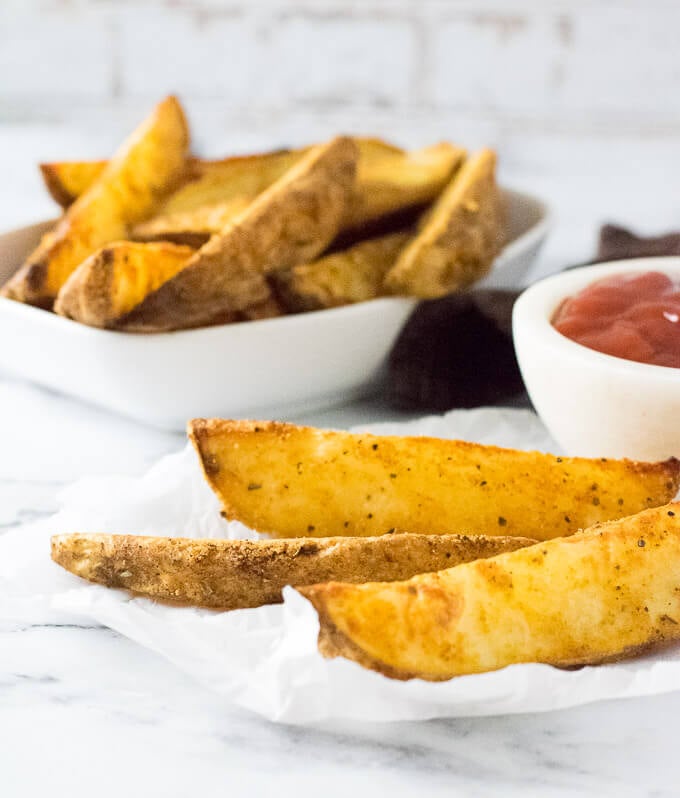 Oven baked steak fries on parchment paper.