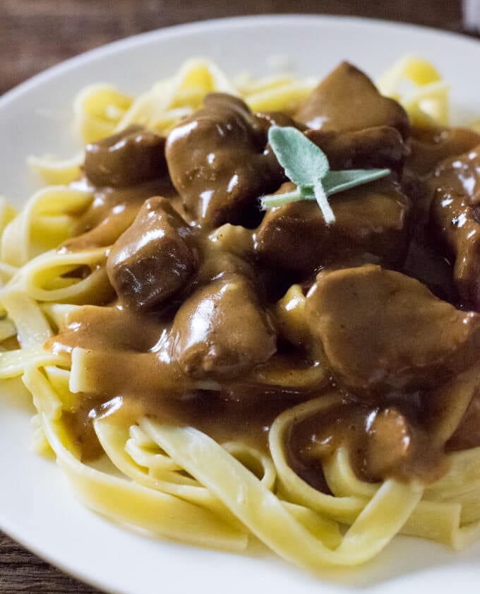 Beef and noodles close up on white plate.