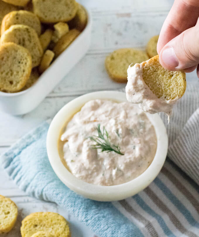 Dipping cracker in creamy smoked salmon dip.