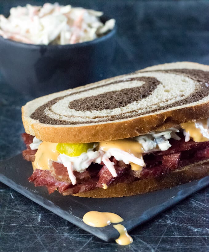 Corned beef sandwich on rye with pickles and coleslaw