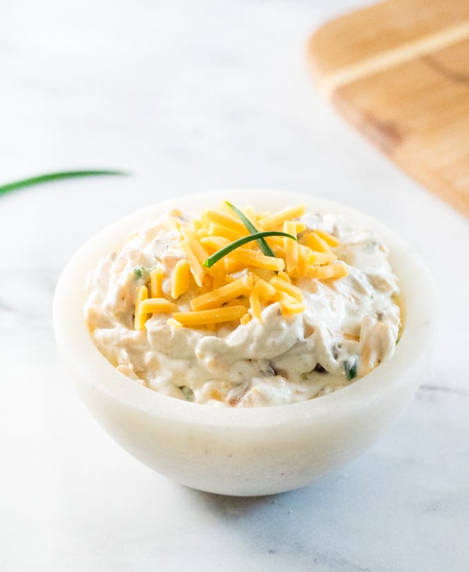 Loaded baked potato dip in white bowl.