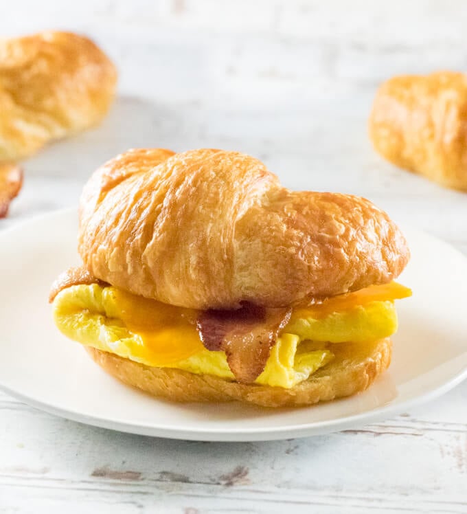 Croissant Breakfast Sandwich sitting on white plate.