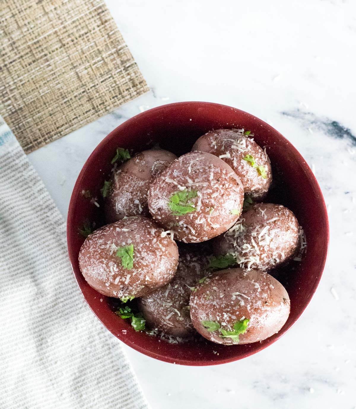 Boiled red potatoes in red bowl viewed from above.