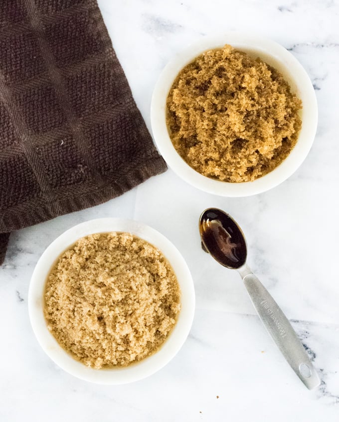 Light and dark brown sugar in separate bowls with molasses covered spoon.