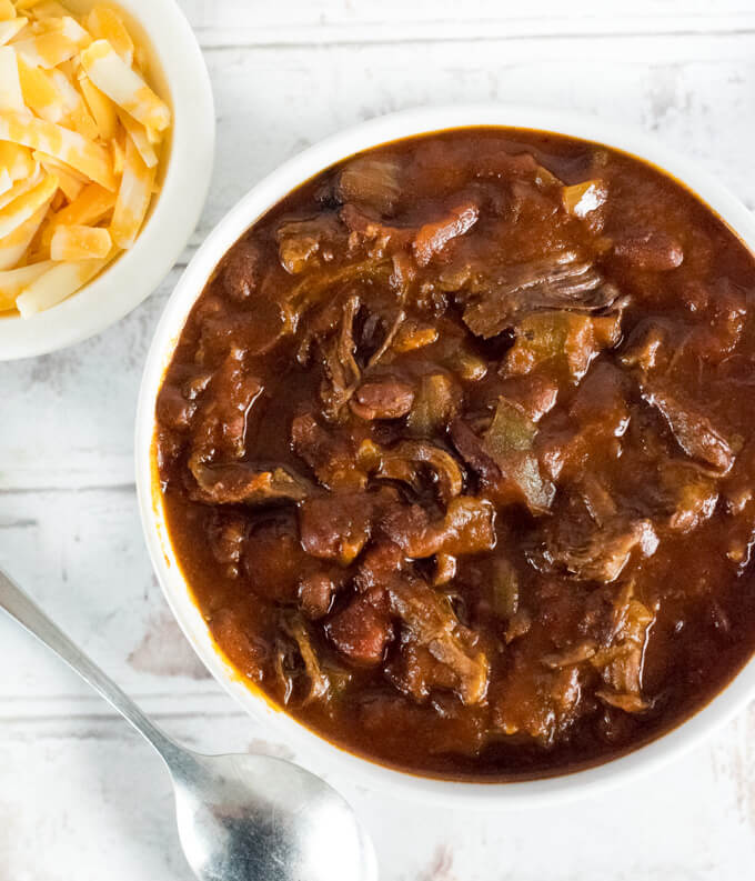 Shredded beef chili with shredded cheese on the side.