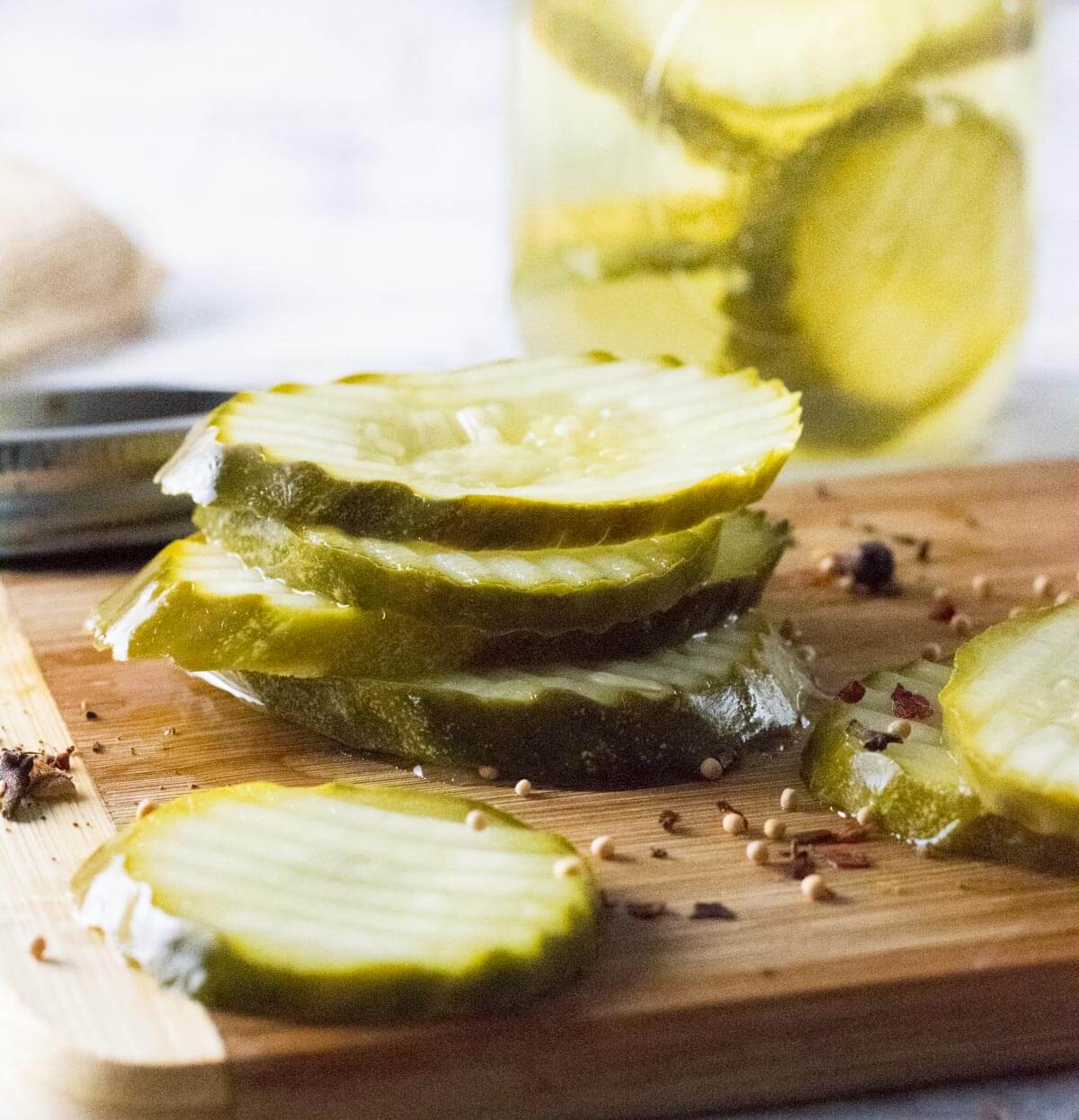 Refrigerator dill pickles stacked up on wooden board.