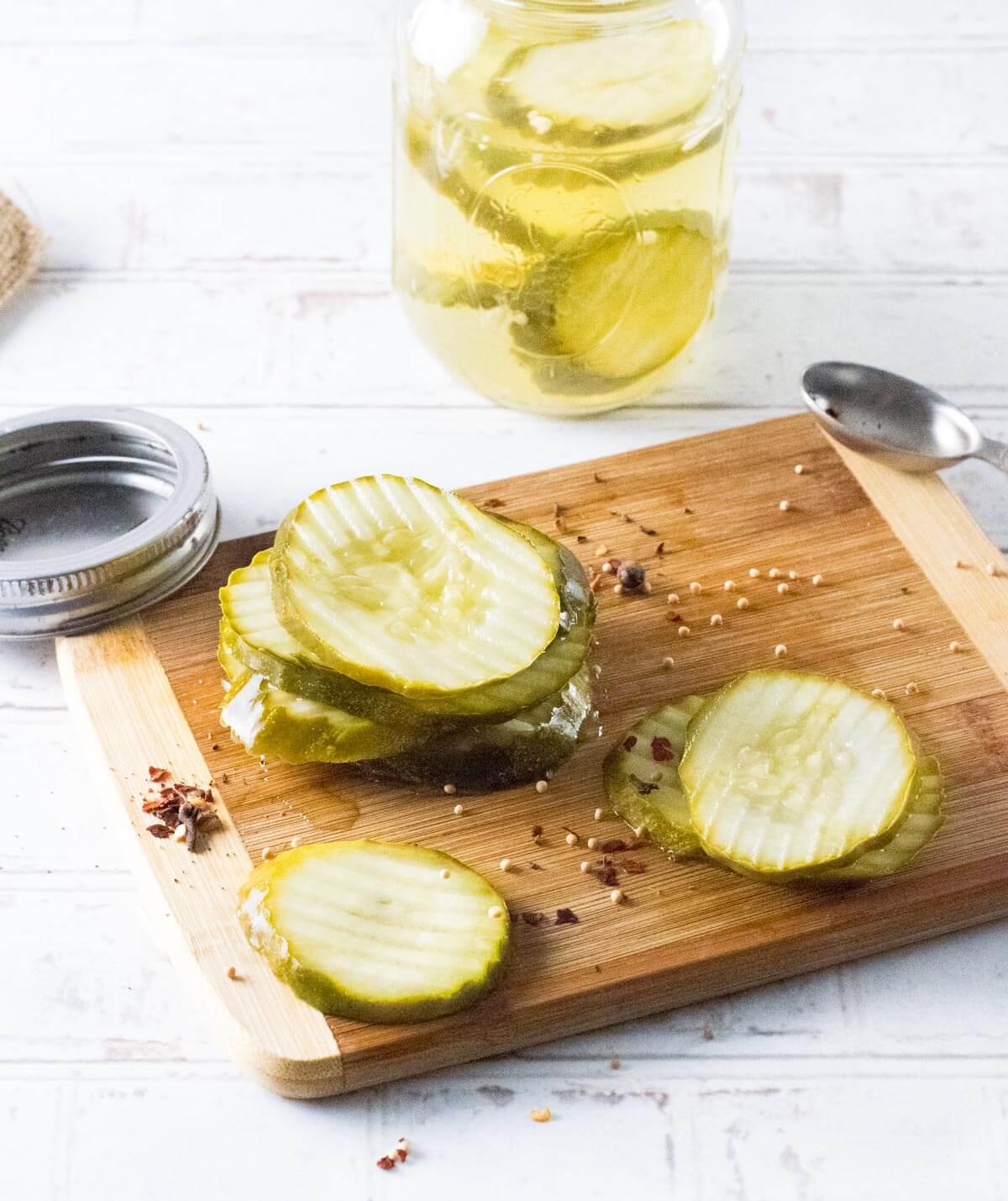 Refrigerator dill pickles on cutting board with seasonings.