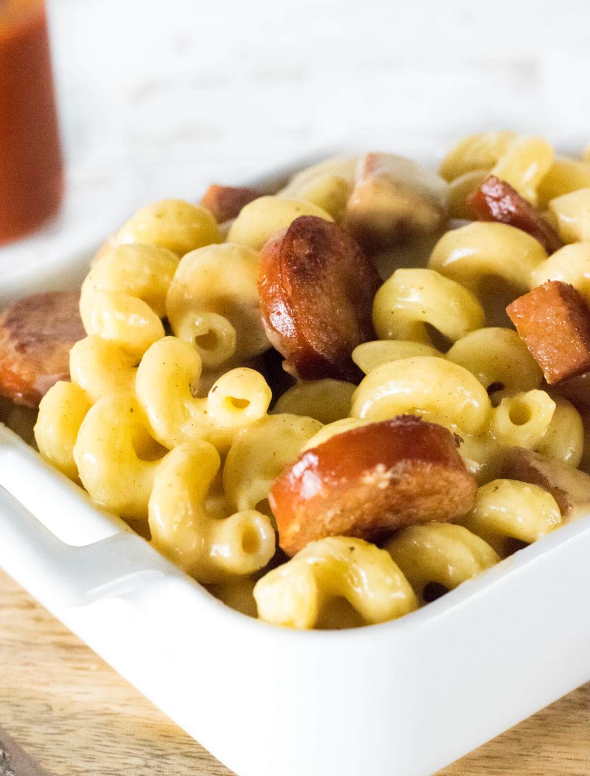 Mac and cheese with andouille sausage in a white dish.