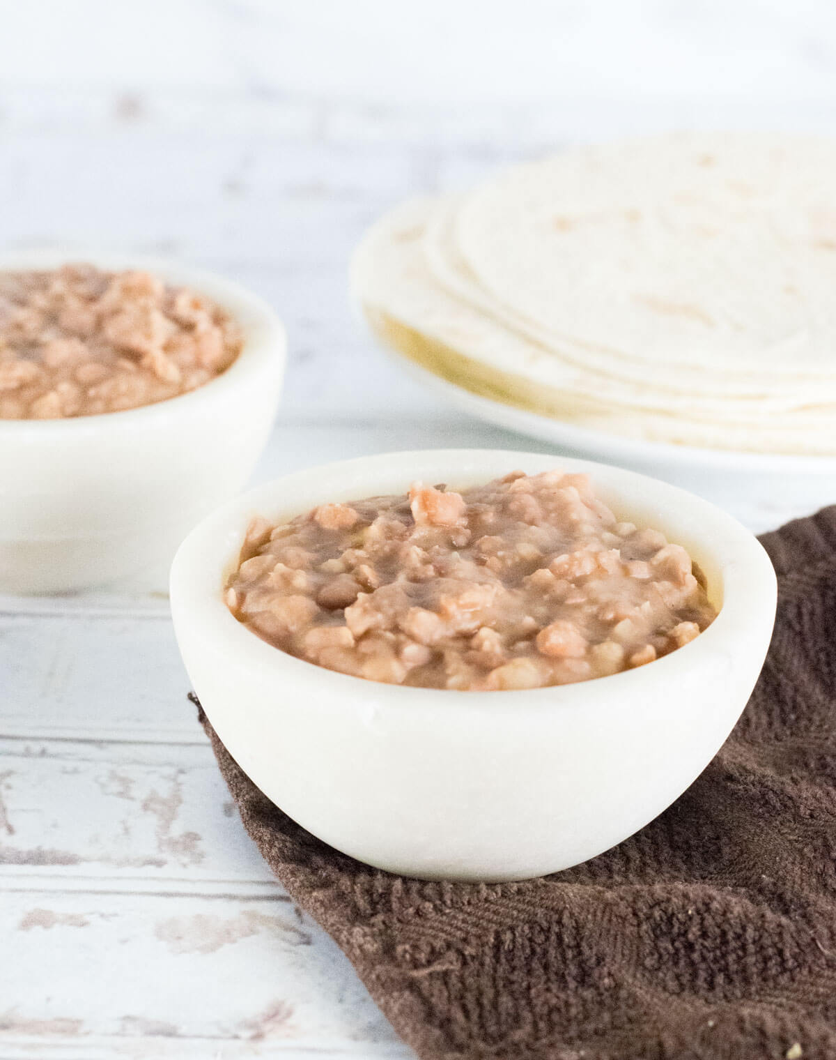 Refried beans with lard in bowl with tortillas.