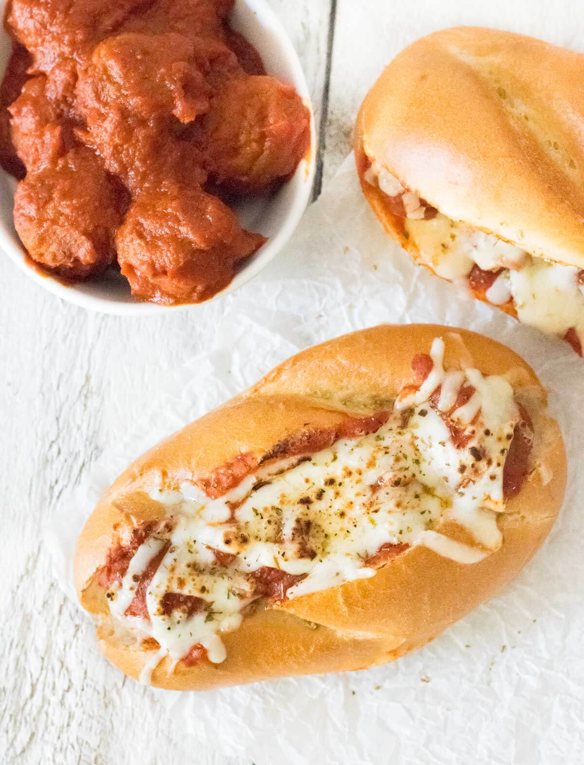 Baked meatball subs with mozzarella cheese on a toasted roll shown from above.