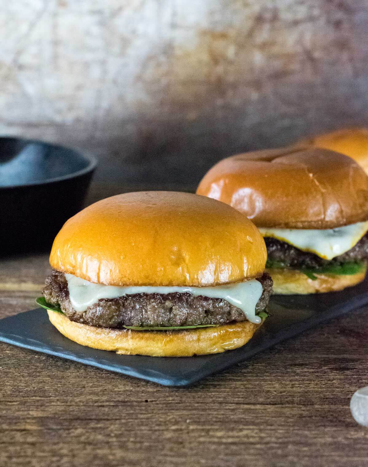 Two Blended burgers resting on black tray.