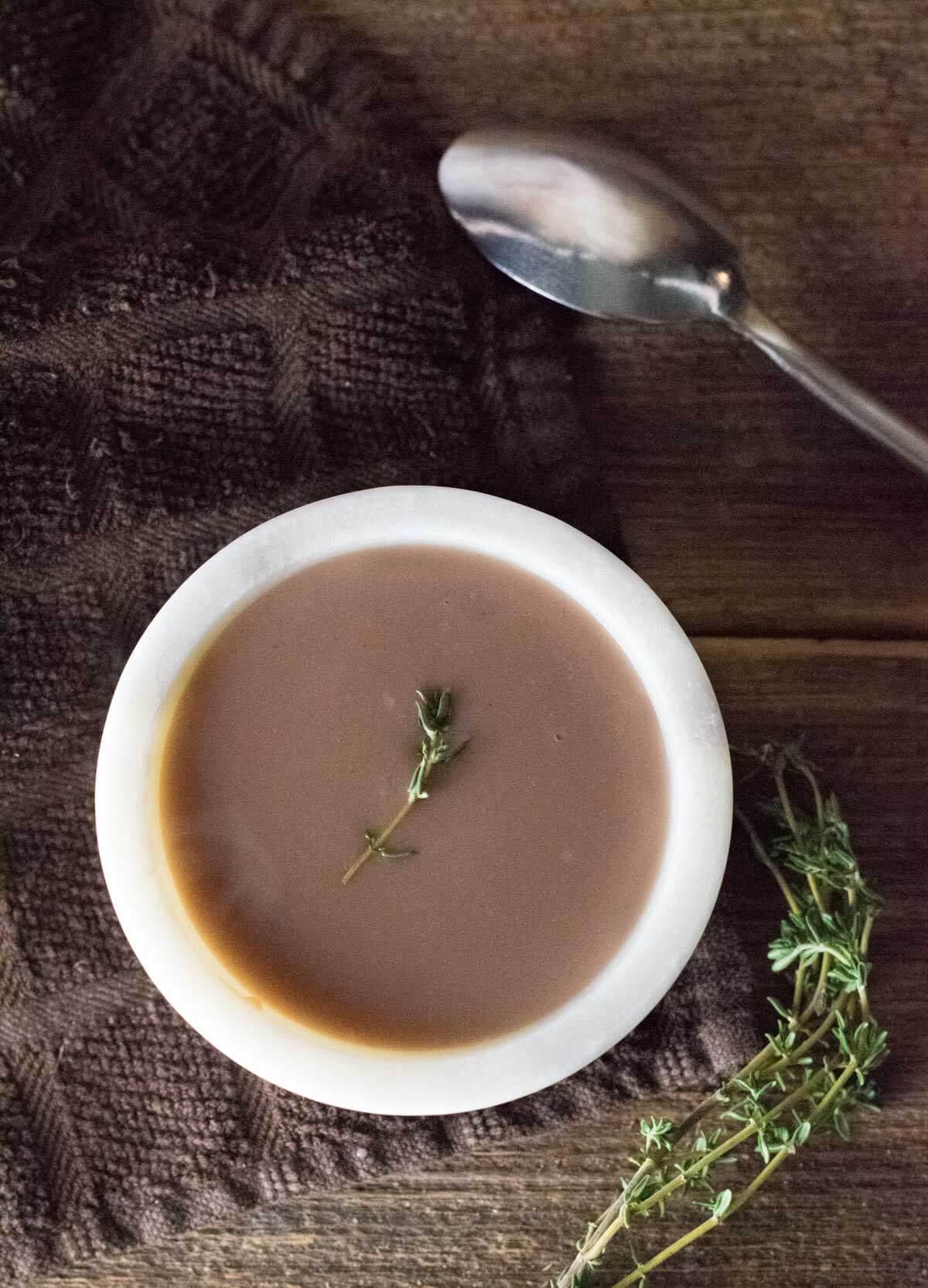 Homemade gravy in a bowl with sprig of thyme.