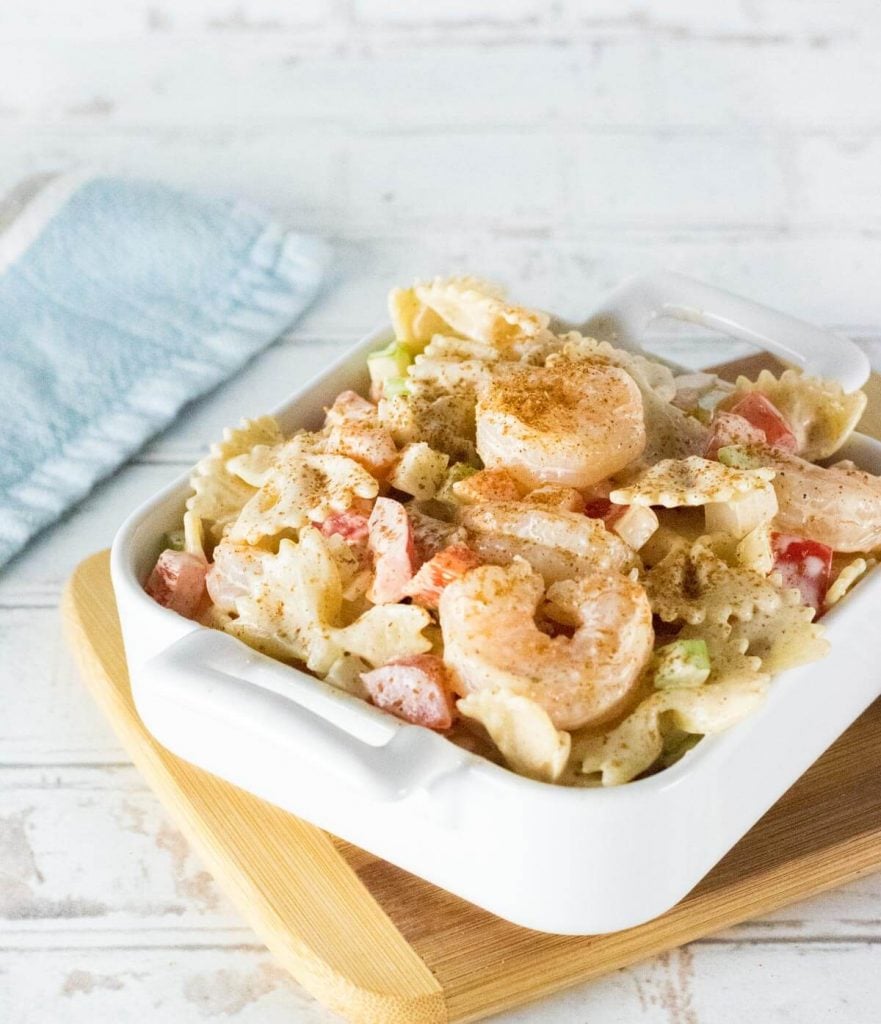 Cajun Shrimp Pasta Salad in white dish on wood platter.