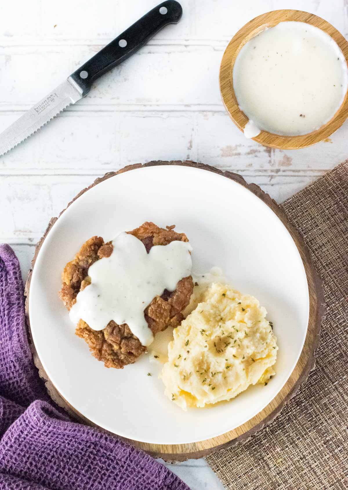 Chicken Fried Venison Steak with mashed potatoes on white plate.