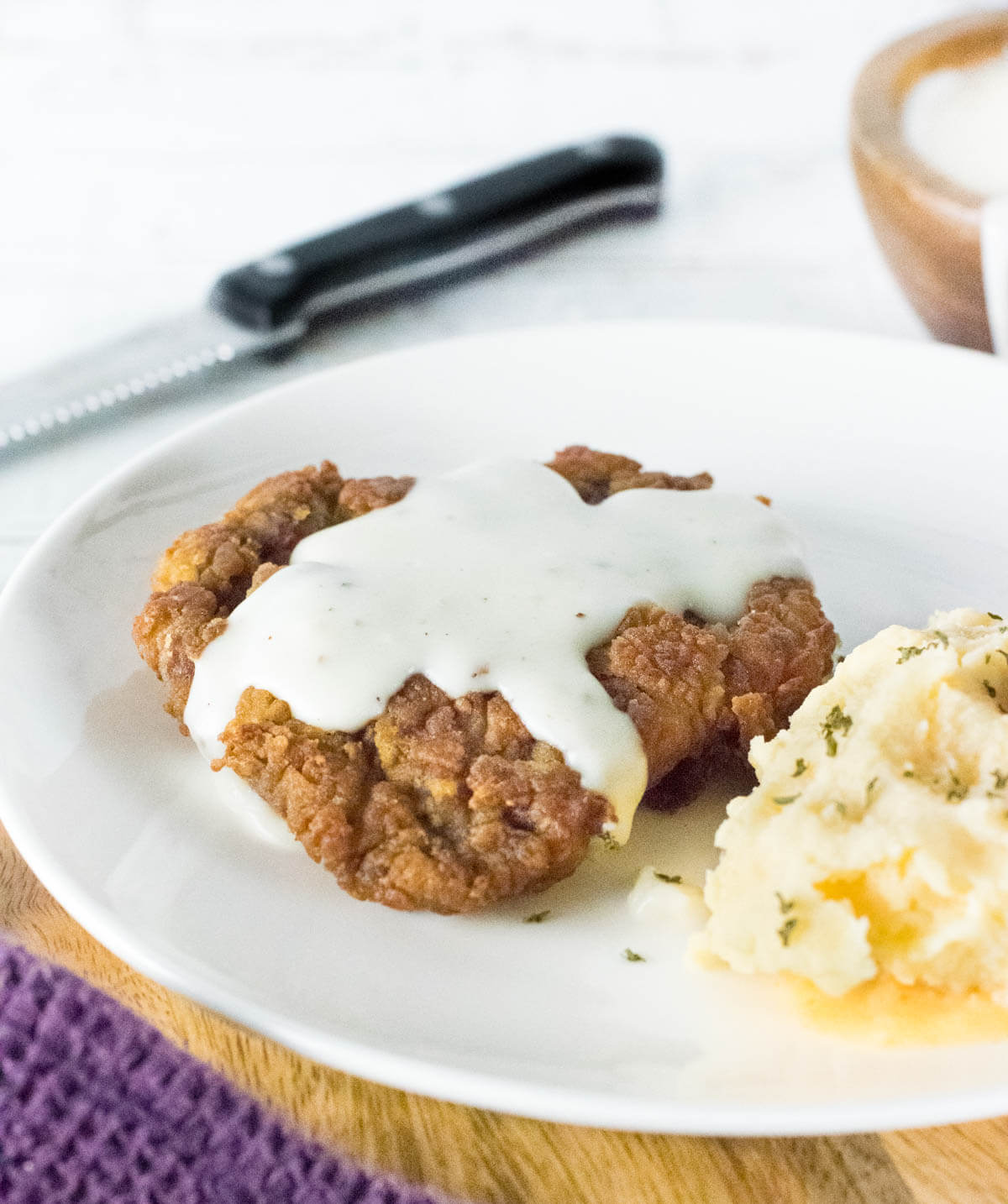 Chicken Fried Venison with white gravy slathered on top next to mashed potatoes.