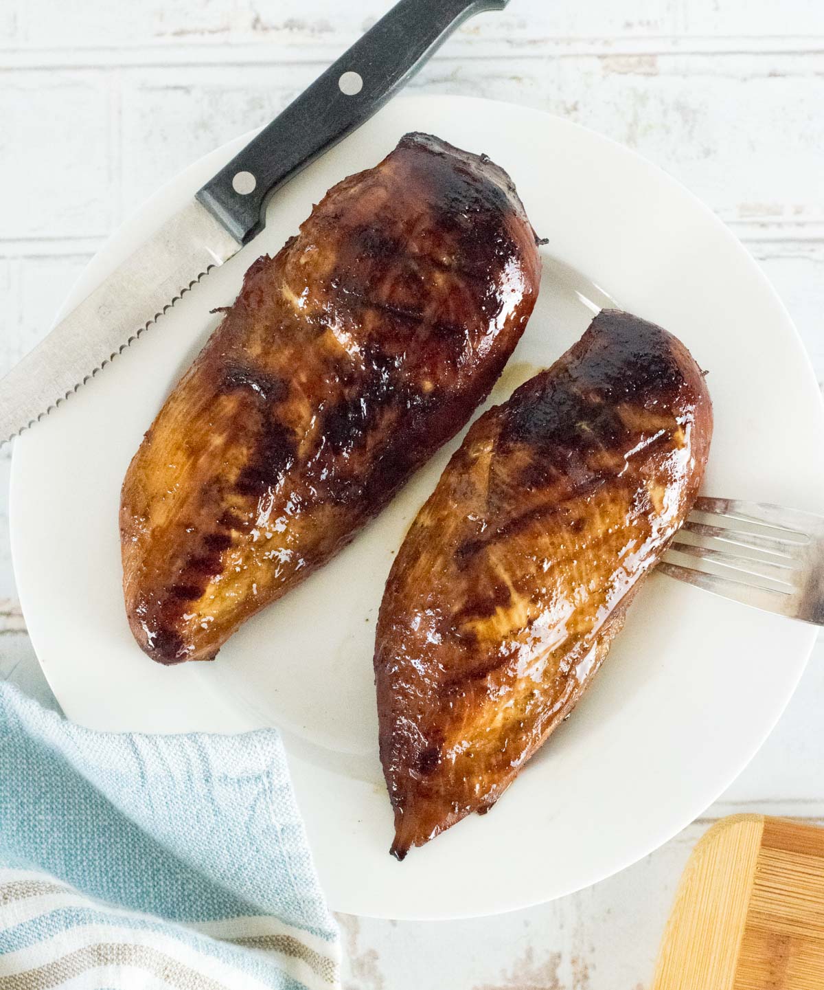 Grilled marinated chicken breast shown from above with knife and fork.