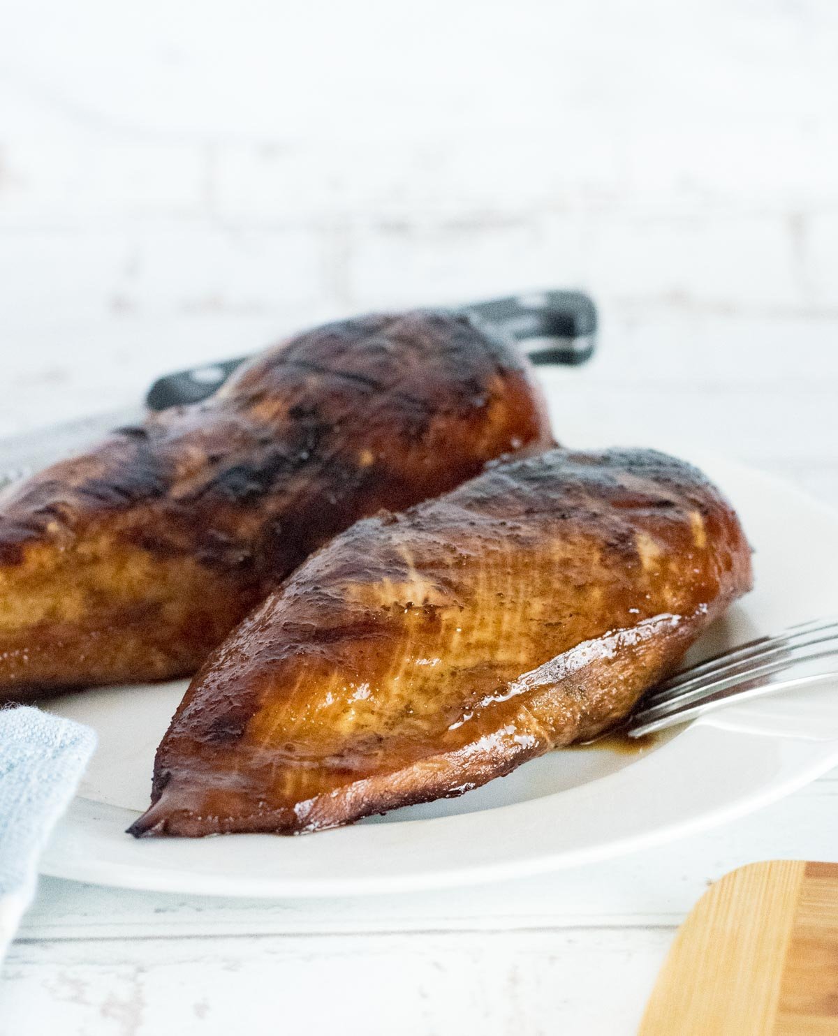 Marinated Grilled Chicken Breasts on white plate with fork.