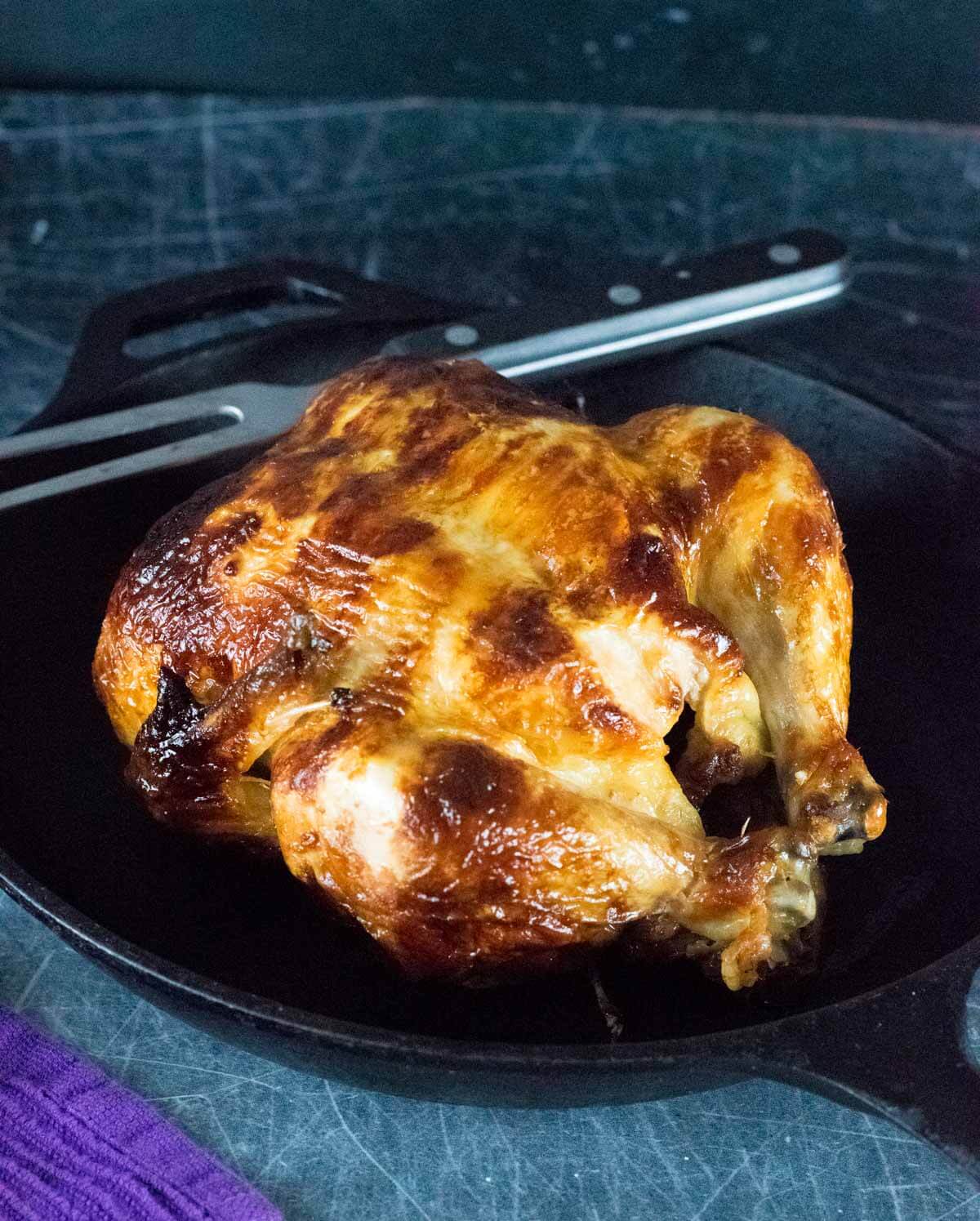 Homemade Rotisserie Chicken resting in cast iron pan.