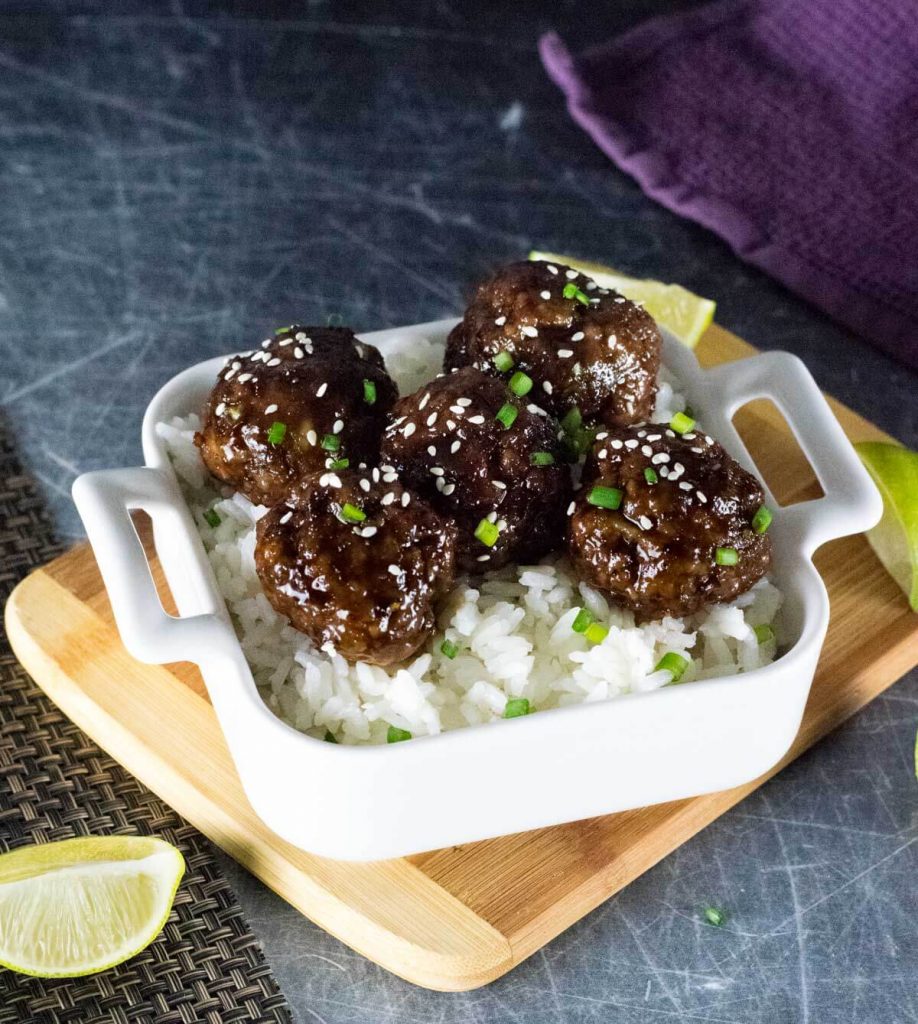 Mongolian meatballs sitting on rice in white dish.