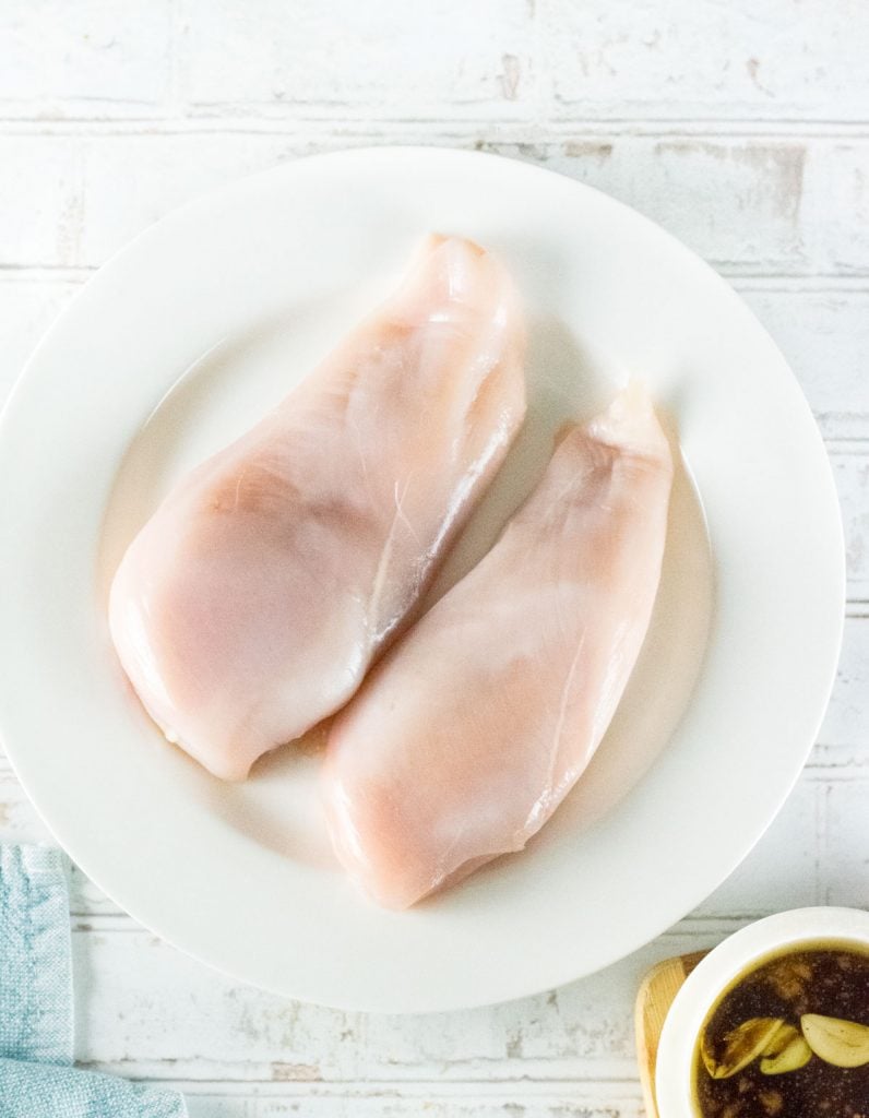 Raw chicken on white plate.