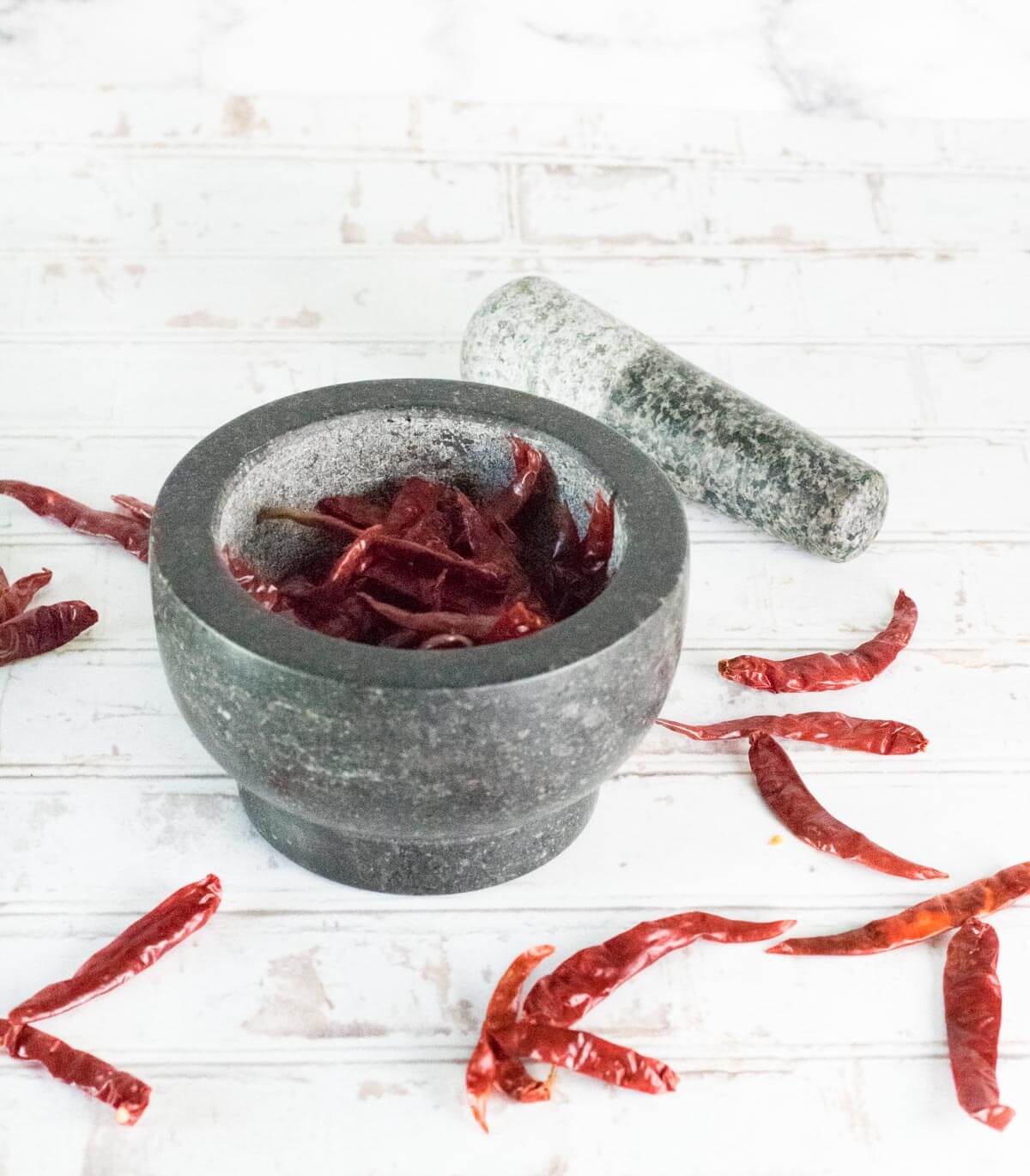 Grinding paprika peppers in mortar and pestle.