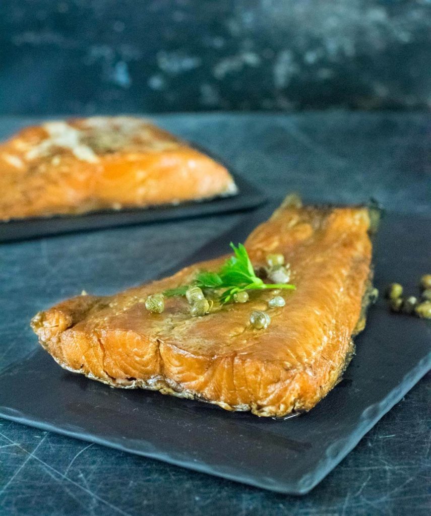 Smoked salmon with capers on black stone.