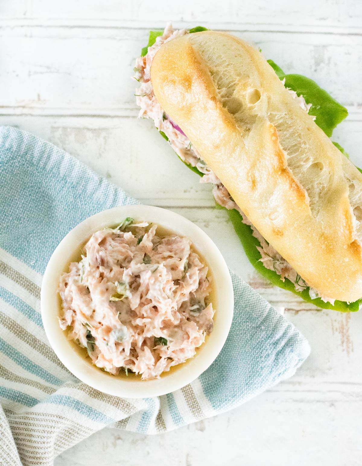 Salmon salad in a bowl next to a sandwich.