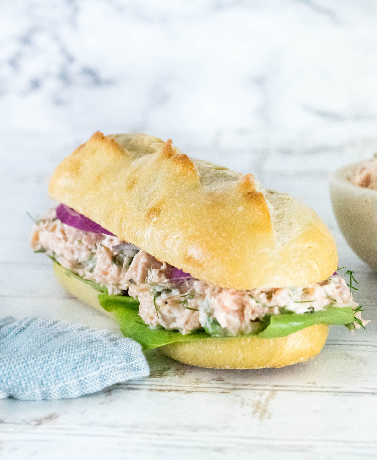 Salmon salad on French bread shown close up.