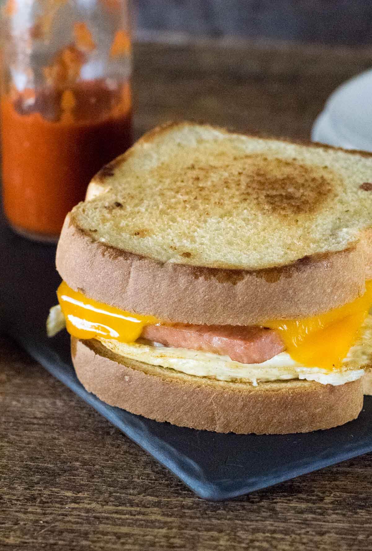 Spam and Egg Sandwich with hot sauce bottle.