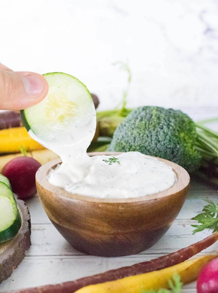 Dipping sliced cucumber into dill dip.