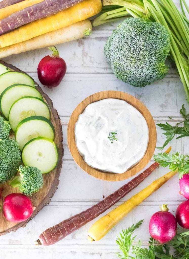 Fresh Dill dip with fresh vegetables shown all around.