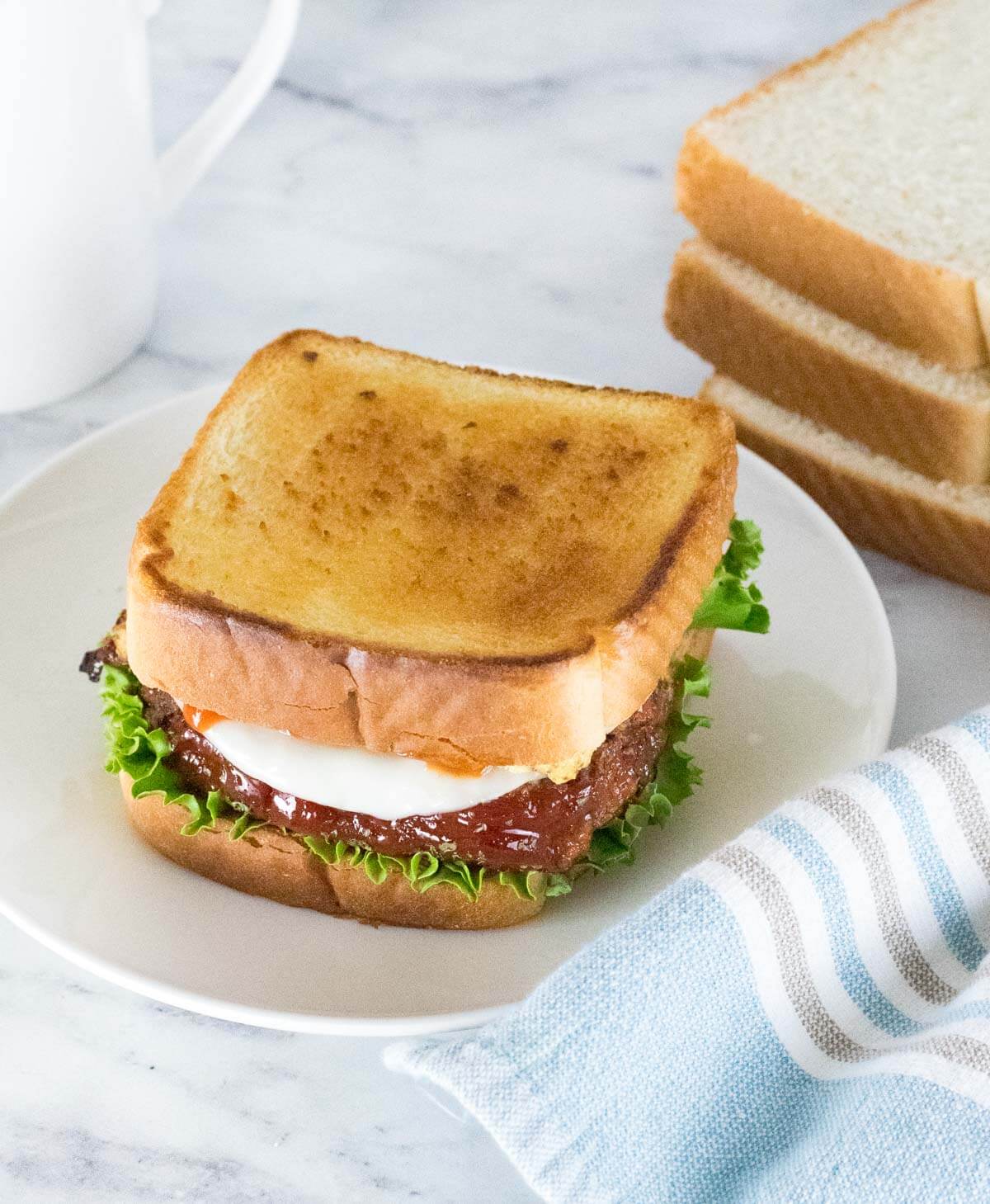 Leftover meatloaf sandwich on white plate.