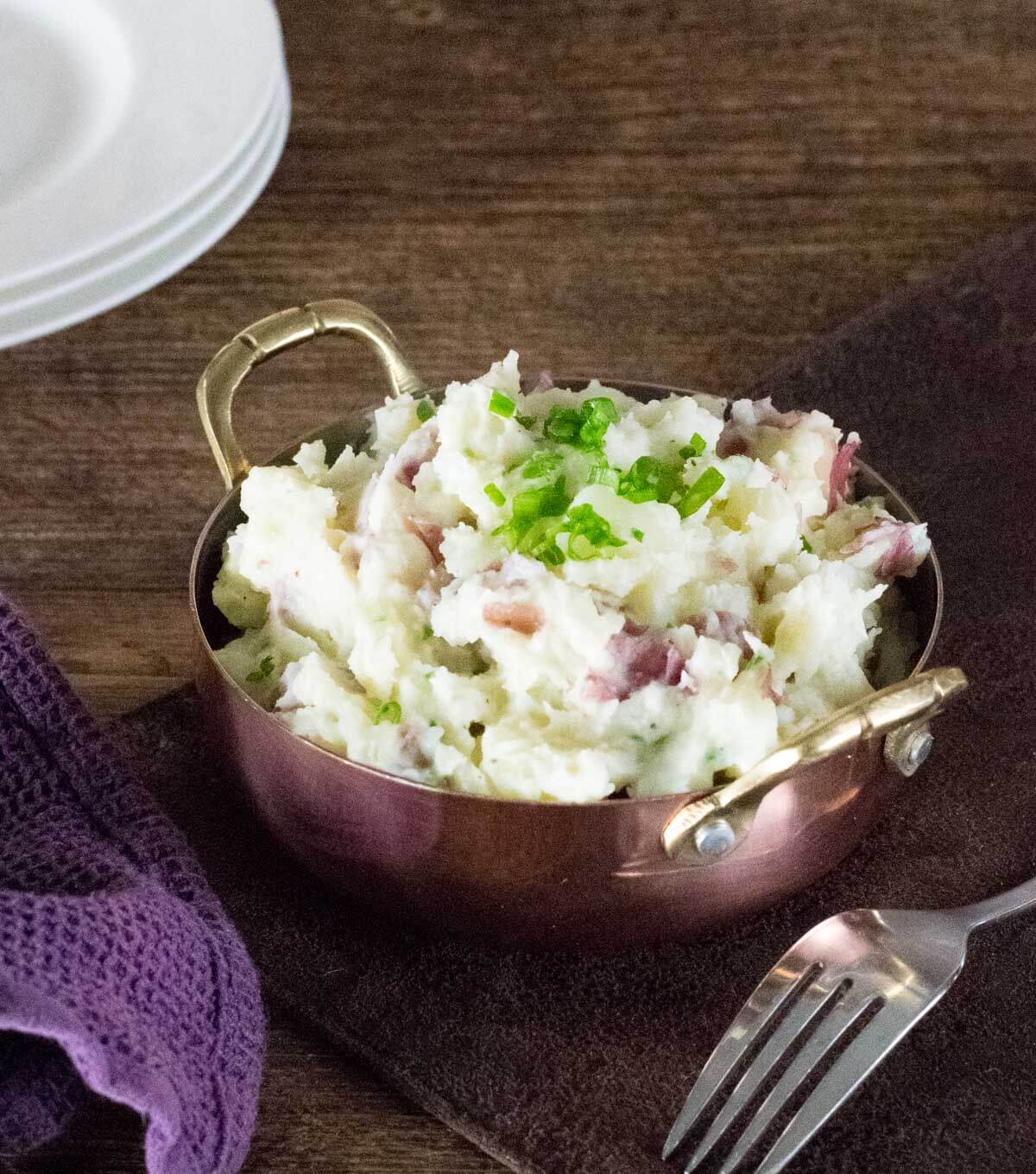 Steakhouse mashed potatoes in serving bowl topped with green onions.