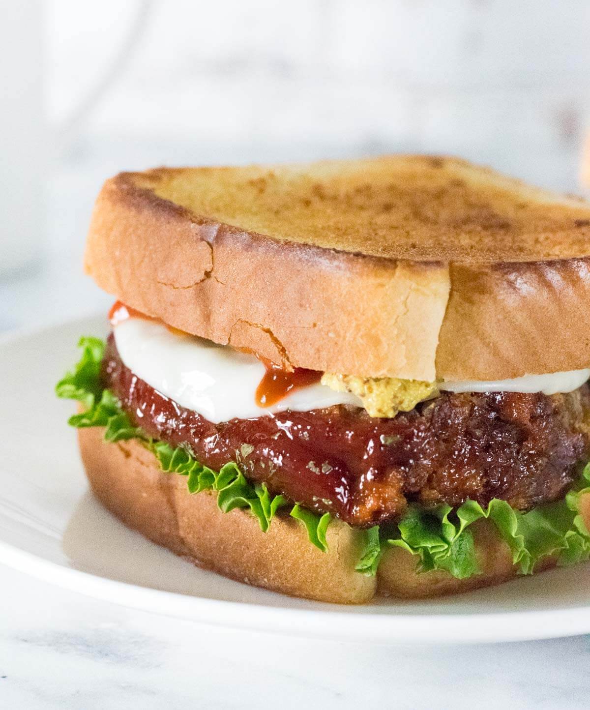 Meatloaf sandwich on Texas toast with ketchup, mustard, and lettuce.