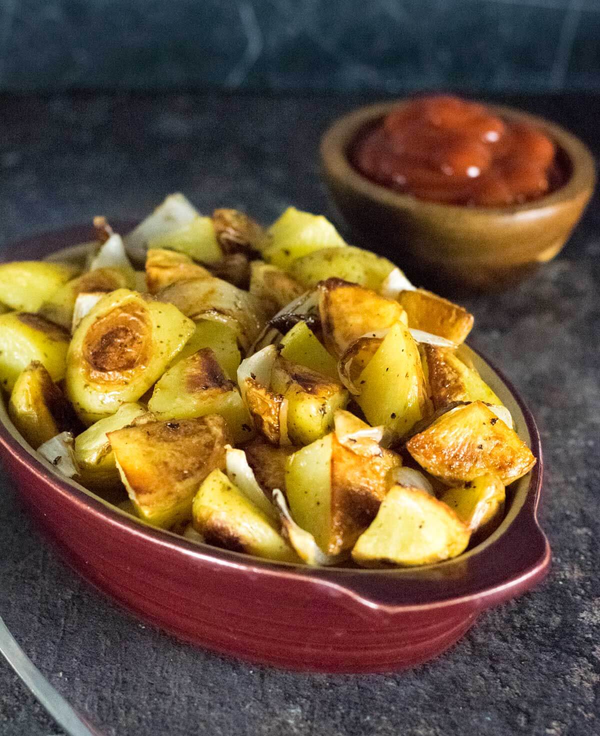 Potatoes and onion with bowl of ketchup.